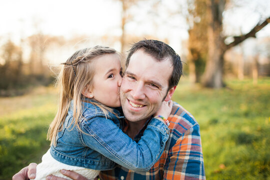 A young girl kisses her dad on the cheek