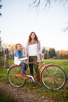Mother and daughter posing with vintage bicycle outdoors