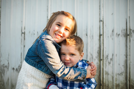 A young girl gives her younger brother a hug
