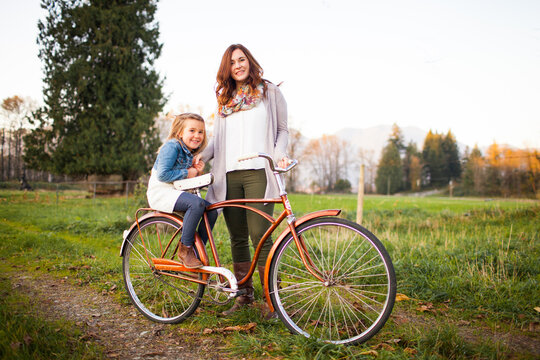 A mother and daughter pose with an old fashioned bicycle
