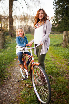 Mother helping young daughter ride a vintage bicycle