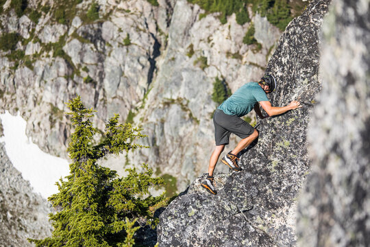 Male climber scrambles up a rocky mountain ridge
