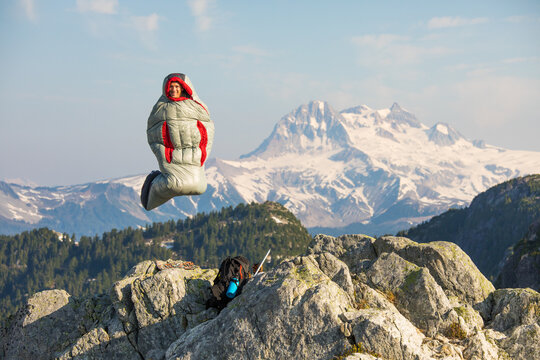Happy man jumping in a sleeping bag on a mountain