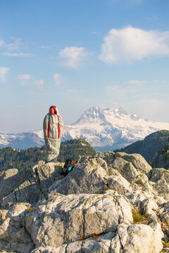 Woman in sleeping bag standing on mountain summit
