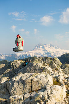 Happy woman in sleeping bag levitates over mountains
