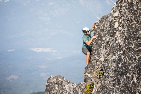 Male climber ascends a granite cliff in the mountains