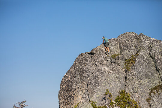 Man scrambling up a sunny rock face