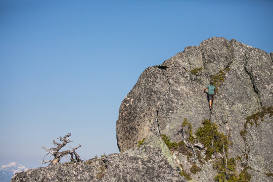 Climber scales a rugged mountain peak on a sunny day