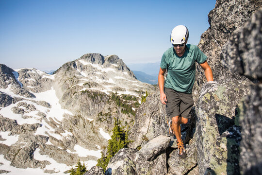 Man with helmet scrambling on a rocky mountain ridge