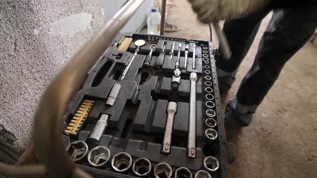 Factory worker man takes tools from professional automotive tool box set.