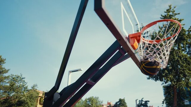 Two male basketball players on a vibrant outdoor court, one soaring for a dunk while the defender leaps to block, energetic streetball action and athletic competition