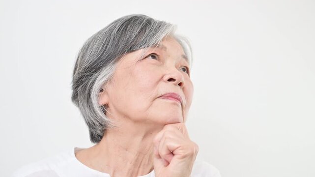 Video featuring a gray-haired senior woman thinking about her pension against a white background&mdash;conveying concerns about retirement savings, pensions, long-term care, and health