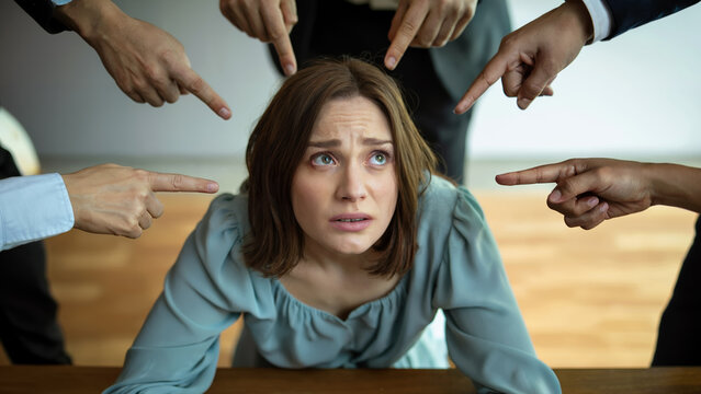 Stressed woman blamed by pointing hands for workplace bullying and anxiety