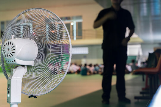 Electric Pedestal Fan Cooling Indoor Hall with Blurred People