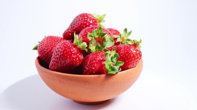 Ripe strawberries in ceramic bowl rotating on white background showcase strawberry freshness, vibrant berry quality, premium fruit presentation for food branding, retail packaging, healthy lifestyle