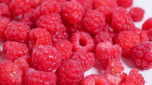 Juicy raspberries rotating in closeup on white background present juicy texture, succulent berry detail, eye catching food composition for social media, packaging, advertising, commercial design