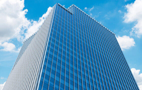 Blue glass tower office building on blue sky cloud background