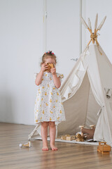 Little child playing with wooden toy camera in nursery. Caucasian girl having fun in teepee tent. Creative childhood activity and role play game. Interior decoration for playroom. © Serg