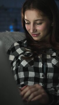 Young Girl Watching A Film On Laptop At Home At Night. Watching Video Online On a Streaming Platform, Vertical Video