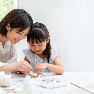 白いテーブルで夏休みの自由研究をする日本人親子
