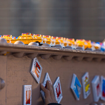 Miniature New York City yellow taxis and decorative souvenirs displayed on a steel railing, reflecting urban travel tourism on the Brooklyn Bridge, Manhattan, USA.