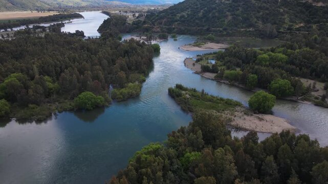 High drone view of winding blue river, sandbars and forested islands in Perales, Maule Region, at the Rio Claro and Rio Maule confluence.