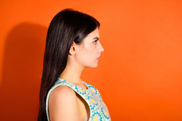 Profile portrait of a young brunette woman in a stylish top against an orange background highlighting casual summer fashion © deagreez
