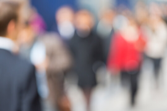 Blurred commuters walking through an urban city street depicting a professional lifestyle and busy rush hour in Lower Manhattan, New York City.