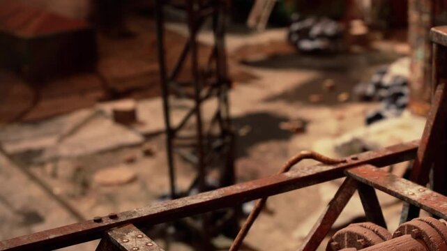 A view of a construction site shows a metal structure nearby. Workers are engaged in tasks on the ground. Tools and materials are scattered around. The setting is busy and active.