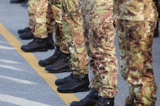 Close-up of soldiers' legs in military camouflage pants and black combat boots standing in formation