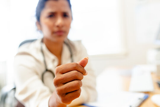 Female medical practitioner extending her hand forward with her fingers curled inward