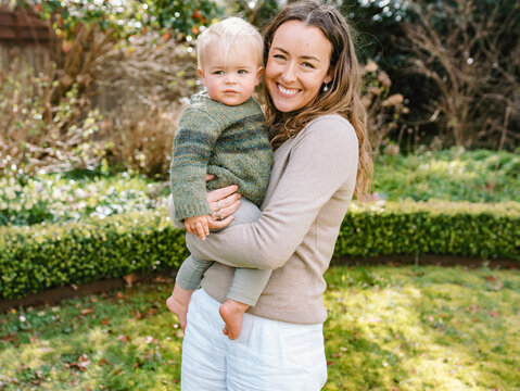 Aussie mum carrying toddler son in the garden