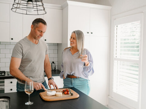 Couple enjoying wine and snacks in bright kitchen