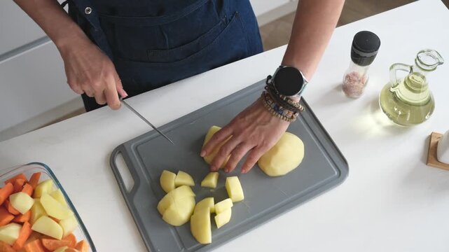 Woman Cutting Raw Potatoes In The Kitchen At Home, Close-Up, Top View