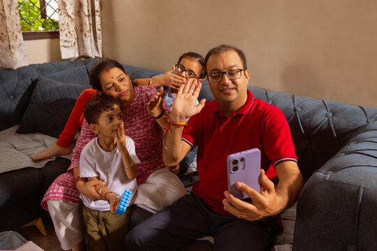 Family waving during video call on sofa