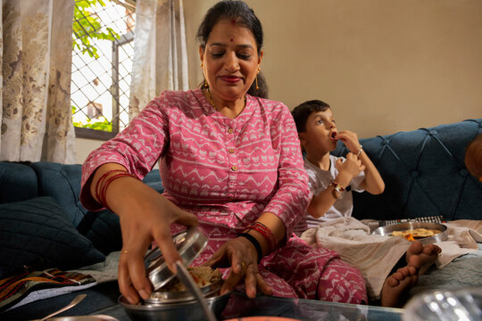 Mother serving food to her son in a cozy living room