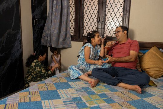 father and daughter cute bonding and mother helping her son in wearing clothes in background
