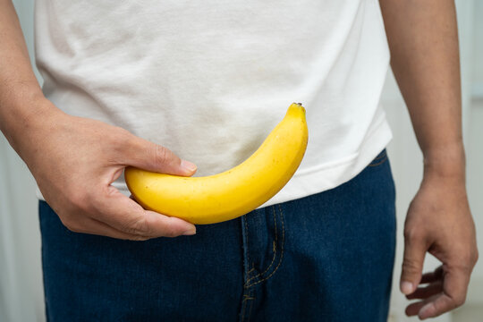 Male stands holding a banana, penis health.