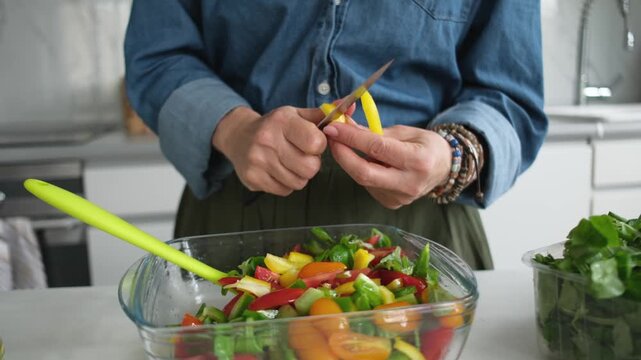 Woman Cutting A Yellow Pepper For A Salad From Vegetables
