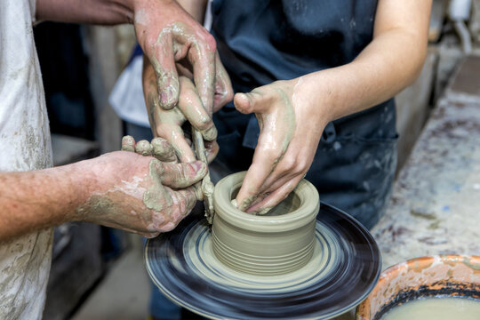  Pottery art class with teacher helping student create ceramic pot