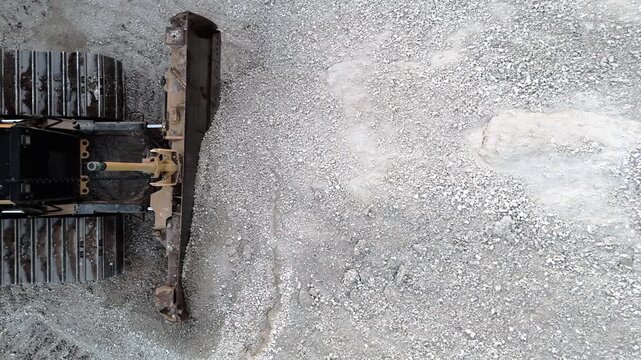 Crawler bulldozer parked in front of a gravel pile at a construction site