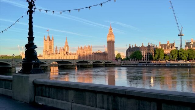 Sunrise view of the Westminster Palace and Big Ben clocktower in London, England, with reflections in the River Thames