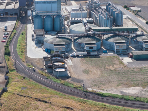 Aerial view of a railway line circling around large steel tanks in a storage facility