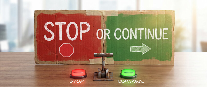 Cardboard sign presenting stop or continue options, a rusted industrial lever and glowing red and green buttons