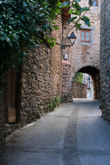 Fototapeta premium Old stone arch in a Catalan village. Traditional architecture and rural tourism. Spain travel. Shallow depth of field. Copy space.