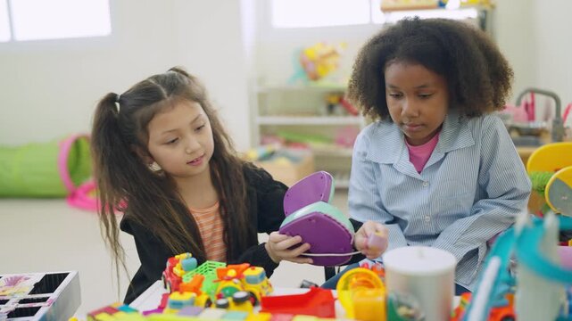 Young Minds at Play: Two young girls, one Asian and one African, engaged in imaginative play with colorful toys in a bright, well-equipped playroom, symbolizing childhood innocence and learning.