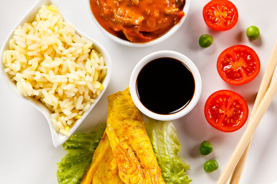 Fried chicken nuggets, white rice and vegetables on white background
