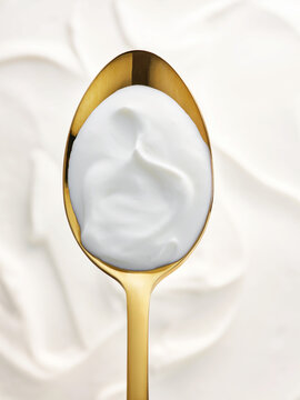 Spoonful of creamy yogurt on gold spoon, premium dairy concept for menu and packaging