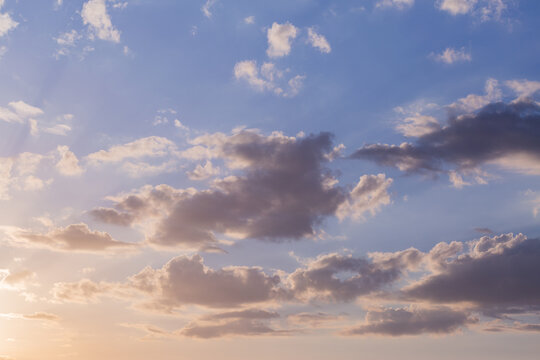 soft pastel morning sky with clouds and rays of sunrise light at dawn