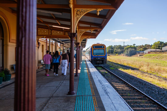 passengers on platform and departing train at rural station